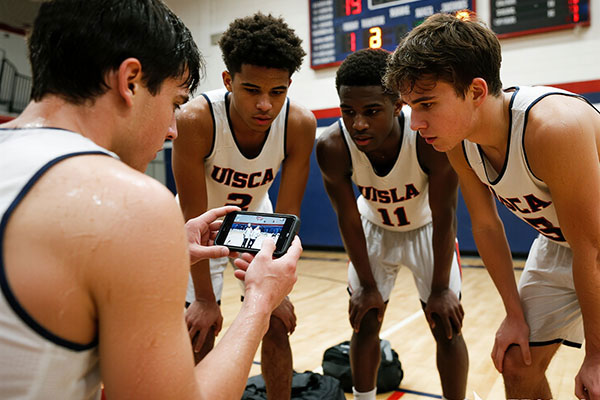 Basketball team memory sharing - sweaty players reviewing game video on phone after practice, celebrating together