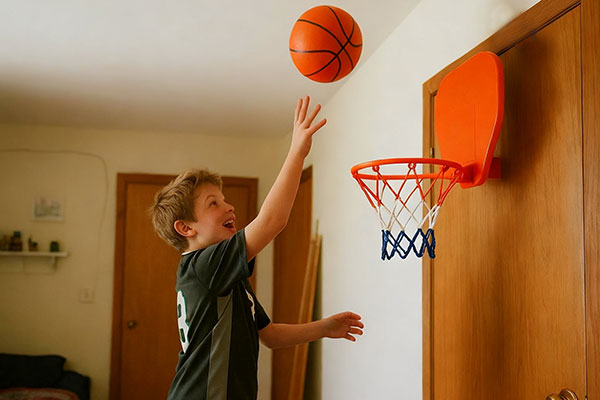 10 year old boy shooting at wall mounted mini basketball hoop on bedroom door
